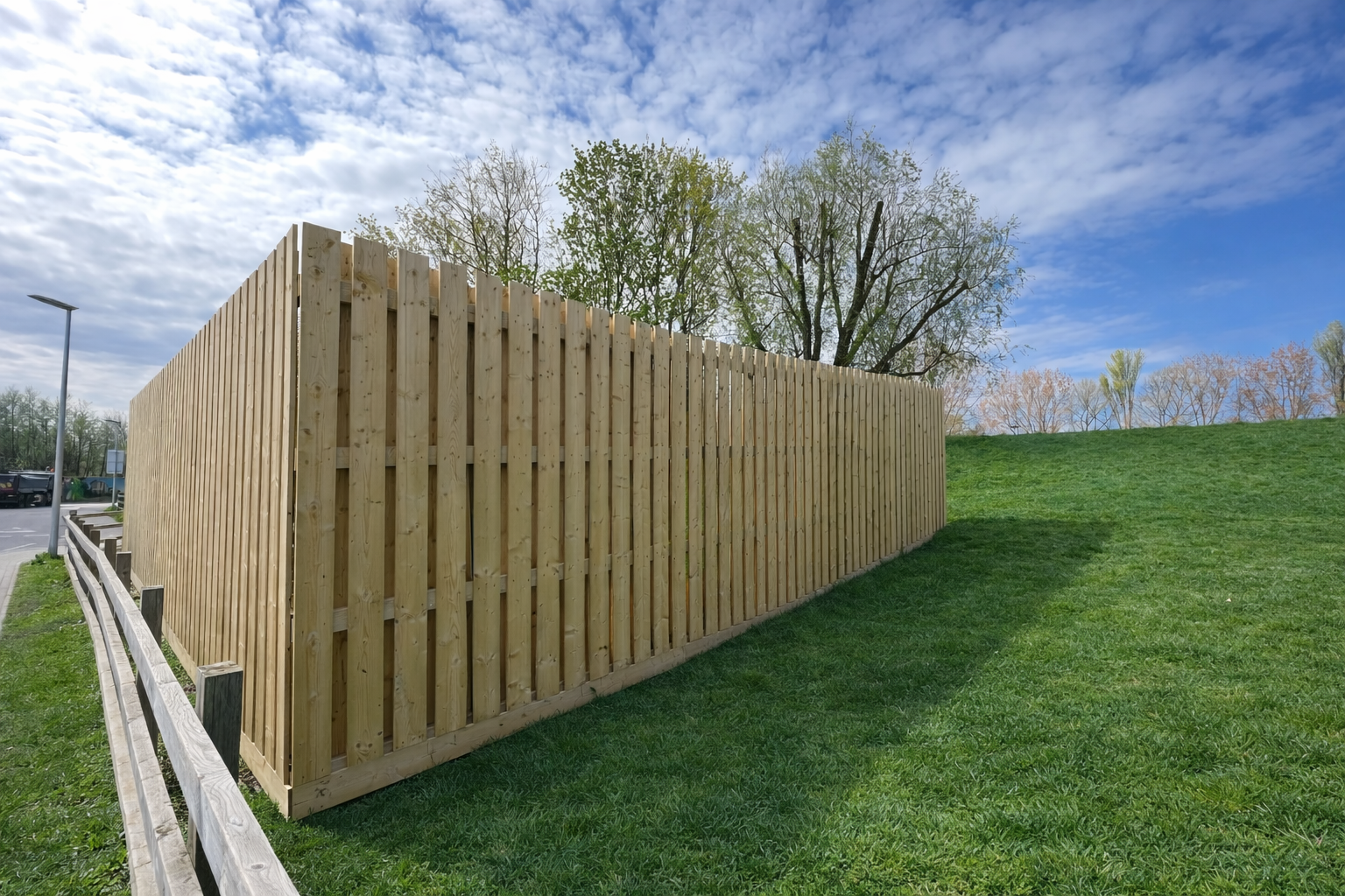 Timber slatted fencing installation on a green hillside